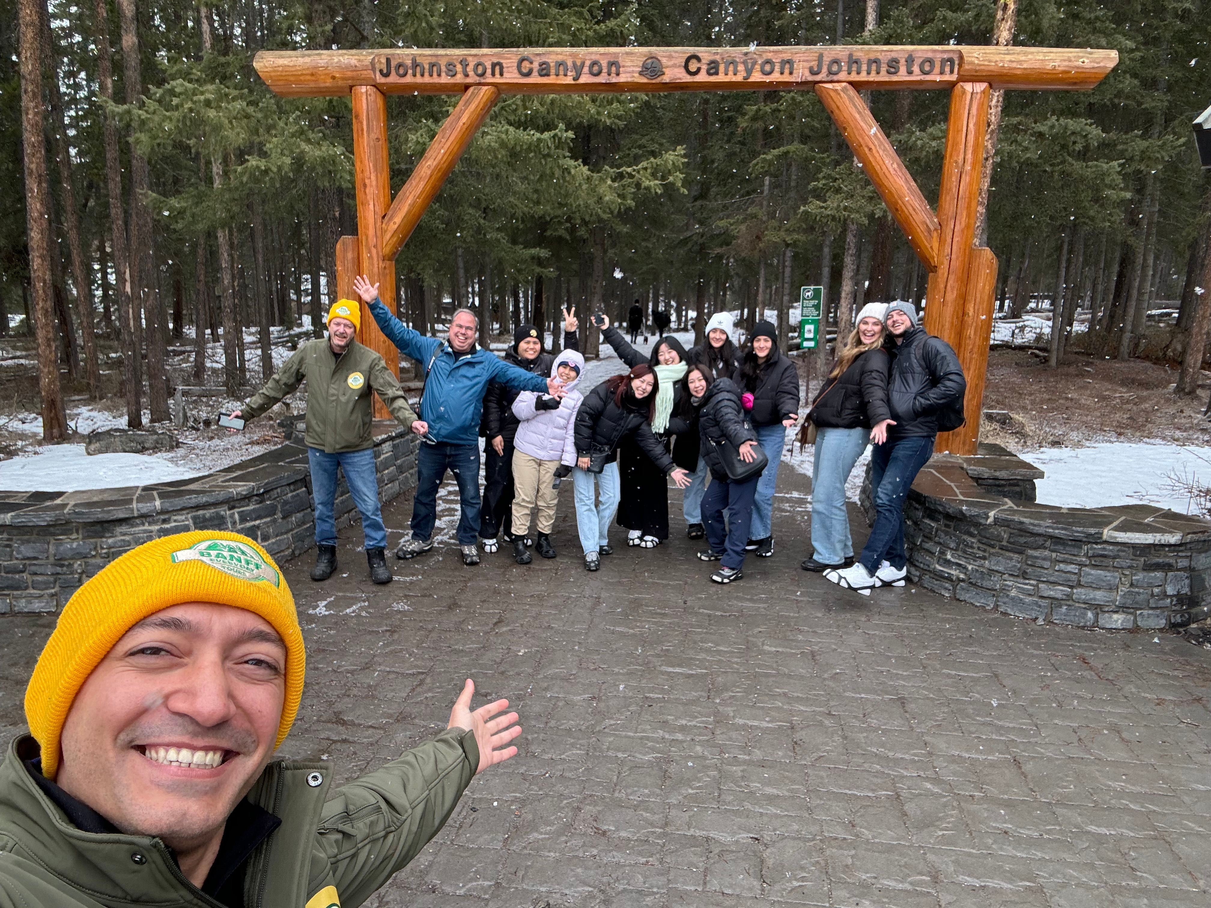 Tour group smiling at Johnston Canyon entrance during Banff day tour from Calgary.