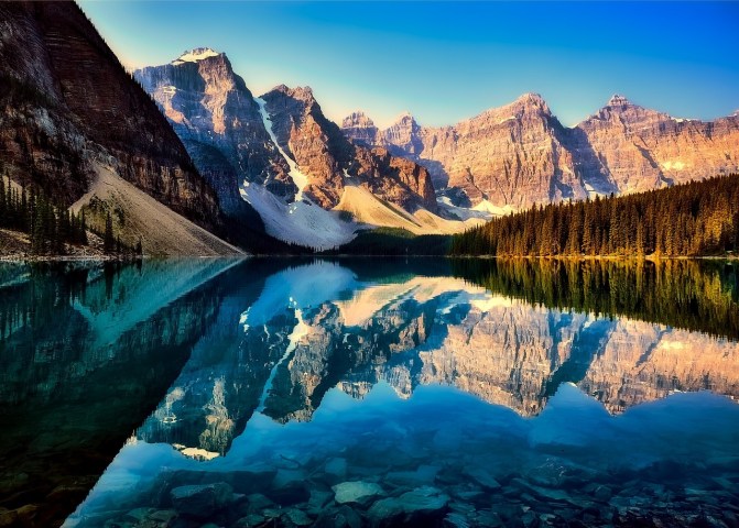 Clear reflection of Rocky Mountains on turquoise Moraine Lake in Banff National Park